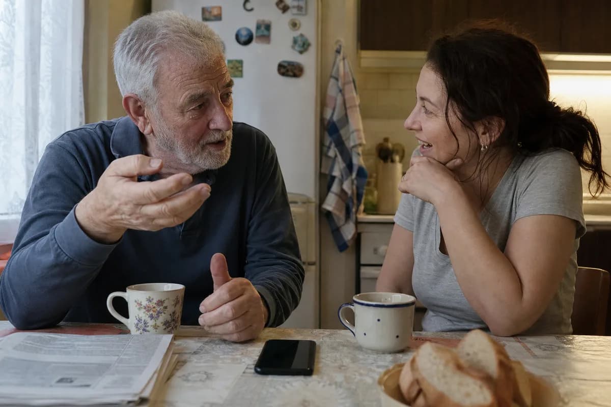 A father telling a story to his adult daughter at their kitchen table