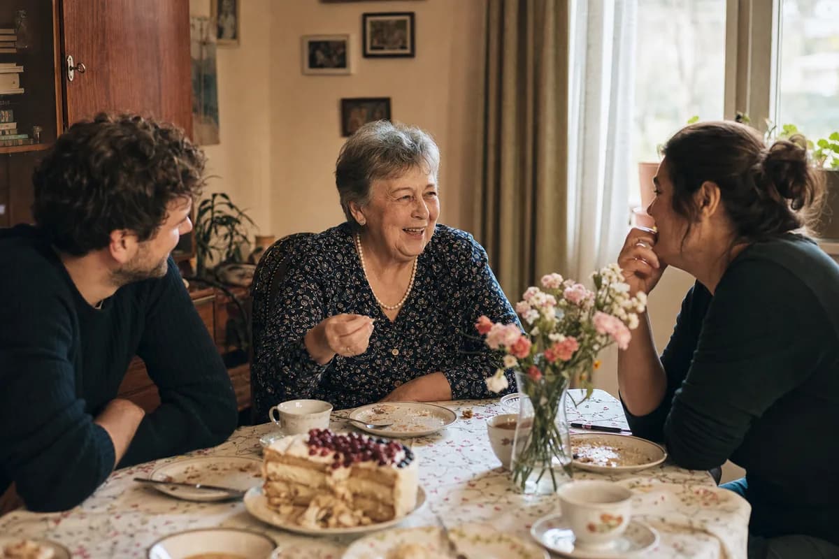 A woman in her sixties laughing with family after a birthday lunch at home.